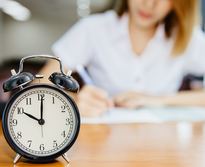 Student studying next to alarm clock.